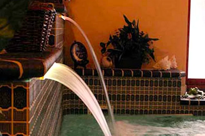 A Sheer Descent waterfall pouring from the tiled wall into the spa