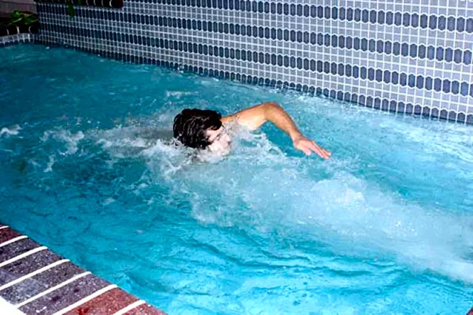 A swimmer in the current near the blue tile wall