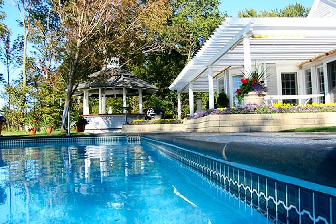 The Dolphin pool with blue porcelain tile under bluestone coping, a gazebo and the white house behind