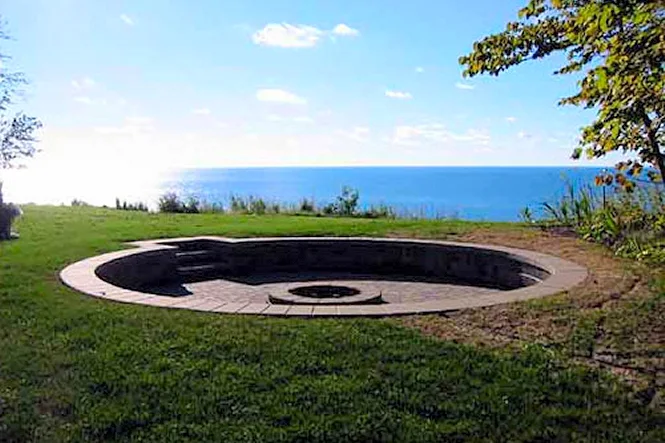 Round sunken fire pit on the lawn above the lake