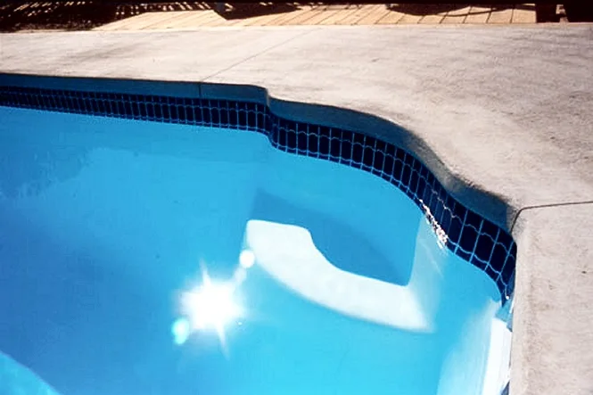 Corner seat at the deep end of the pool, with tile and coping