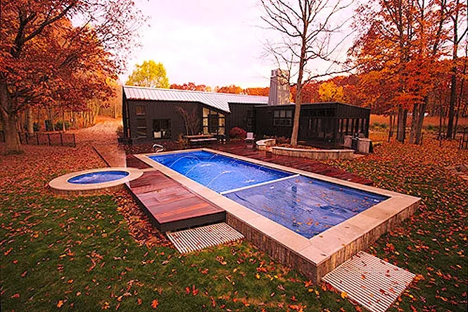 The long Luxor Deep pool and round spa in a wood deck, surrounded by fall color