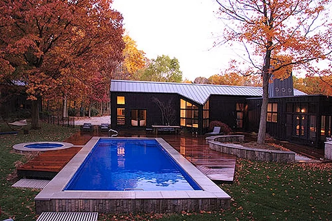 The pool and spa from across the yard, with the dark house behind