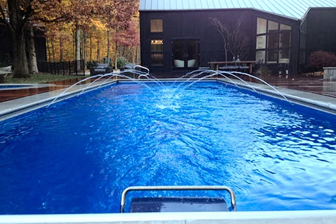 The pool from the deep end with jets running and the house beyond