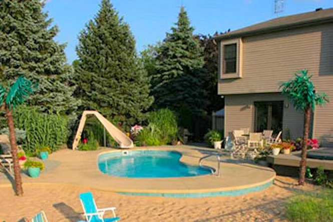 The pool, slide, sand beach and palm-tree decorations in the backyard