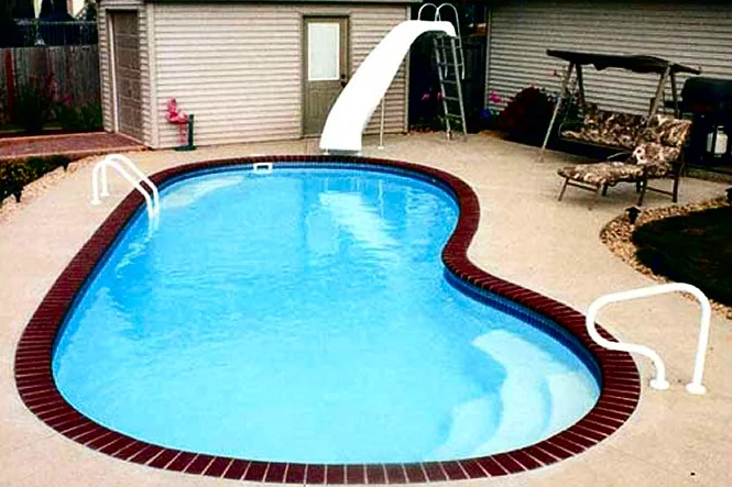The kidney-shaped pool with a slide and the house behind
