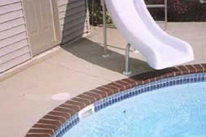 The slide beside the brick-edged pool and the house siding