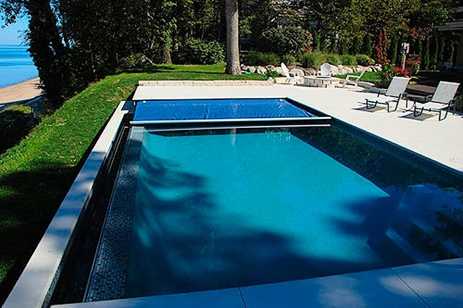 Aerial view of the rectangular pool and deck with the lake past the trees