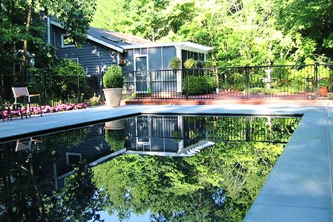 Morning light on the Monte Carlo pool and pool house, with trees behind