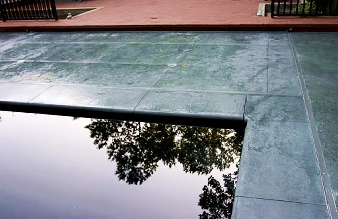 Powder-coated automatic cover track along a Monte Carlo pool, matched to the colored concrete deck