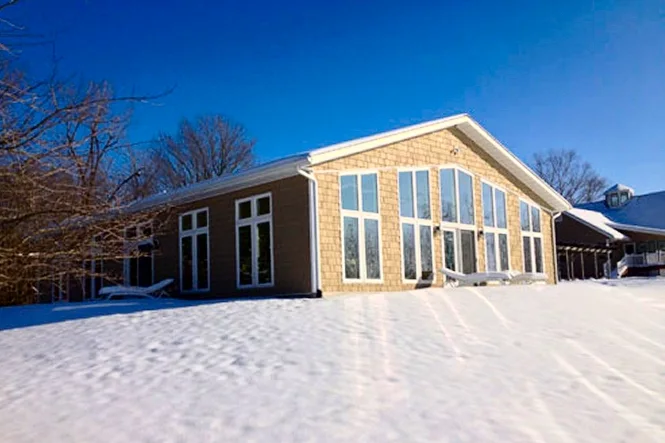 The natatorium building from outside, with tall windows, in winter snow