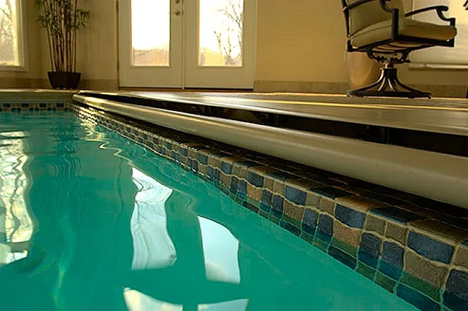 Close view along the pool edge, with tile and the deck in the indoor room