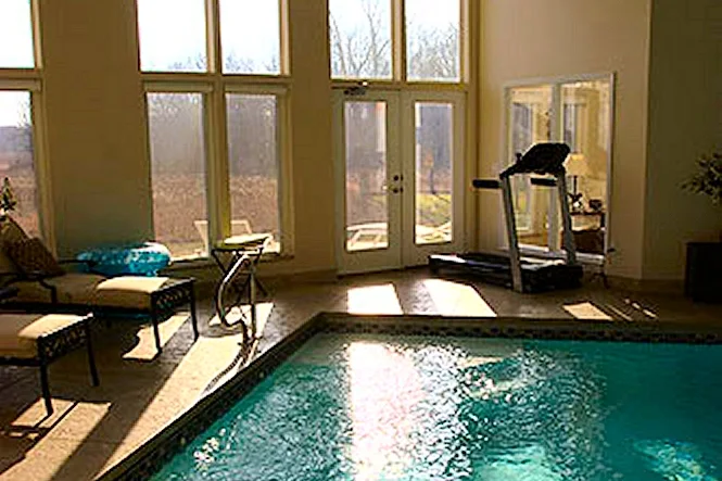 The pool steps and a treadmill by the windows of the pool room