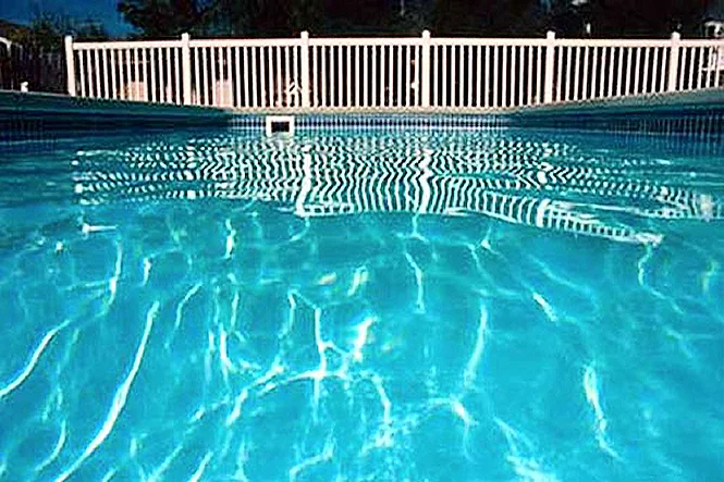 Sunlit blue water and the white fence, seen from water level
