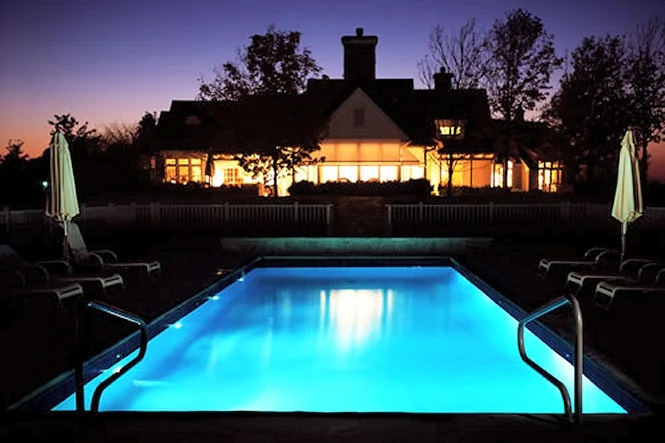 The pool lit at dusk in front of the house