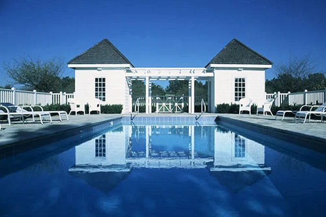 The white bath house and pump room reflected in the still pool