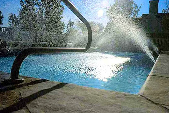 A spray fountain arcing into the pool beside a curved handrail