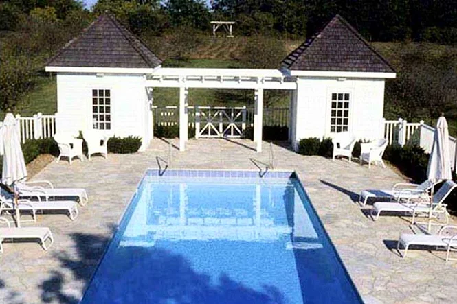 The bath house and pump room with a pergola between them, behind the pool