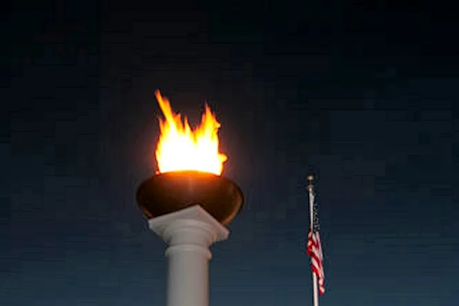 A flame torch burning on top of a white column