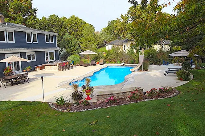 Freeform Taj Mahal Deep fiberglass pool with a slide, a wide concrete deck and lawn in Stevensville, MI