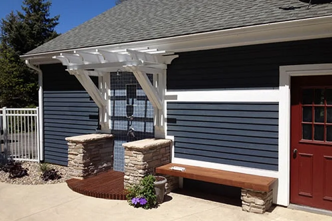The pool house with a white pergola, stone piers and a bench