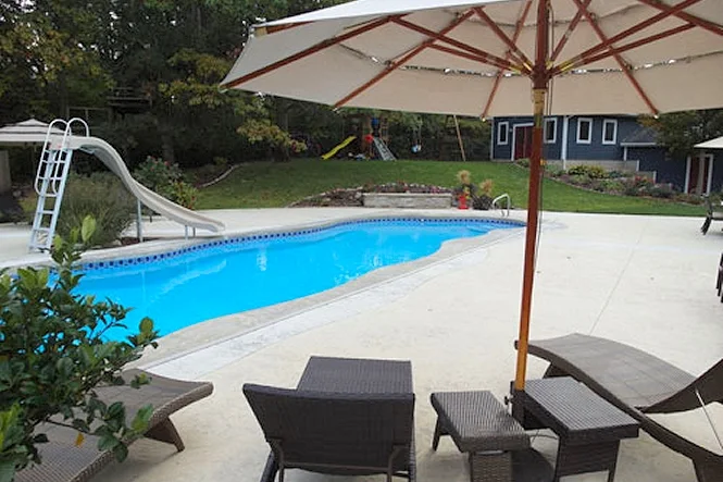 The pool with an umbrella, lounge chairs and the slide